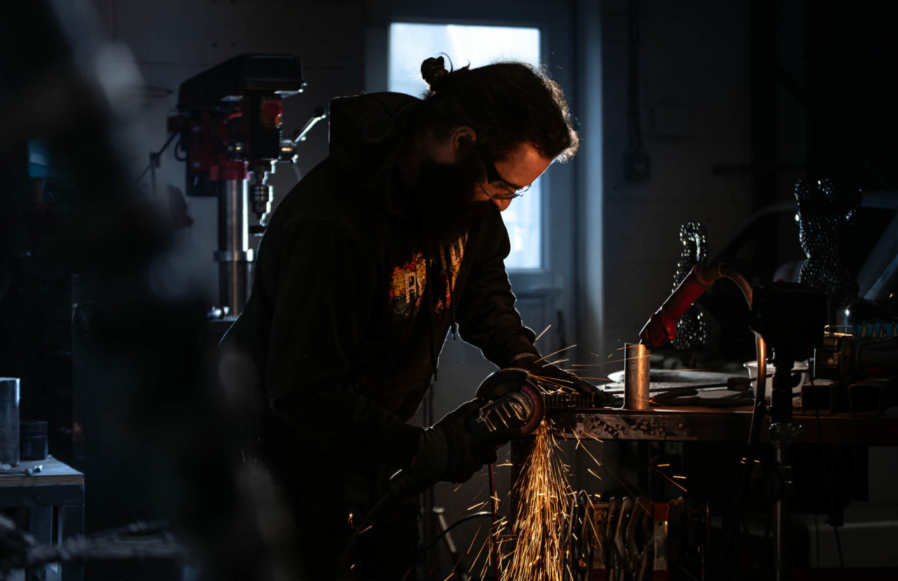 Jason grinding metal at a workbench in the Rebuild Custom workshop