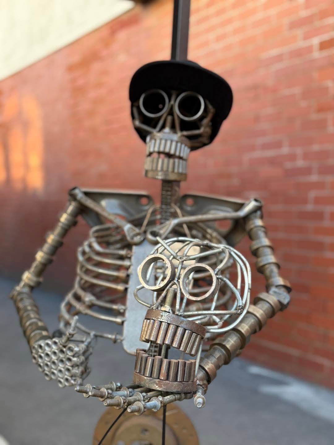 Large scrap-metal skeleton holding a smaller skeleton head