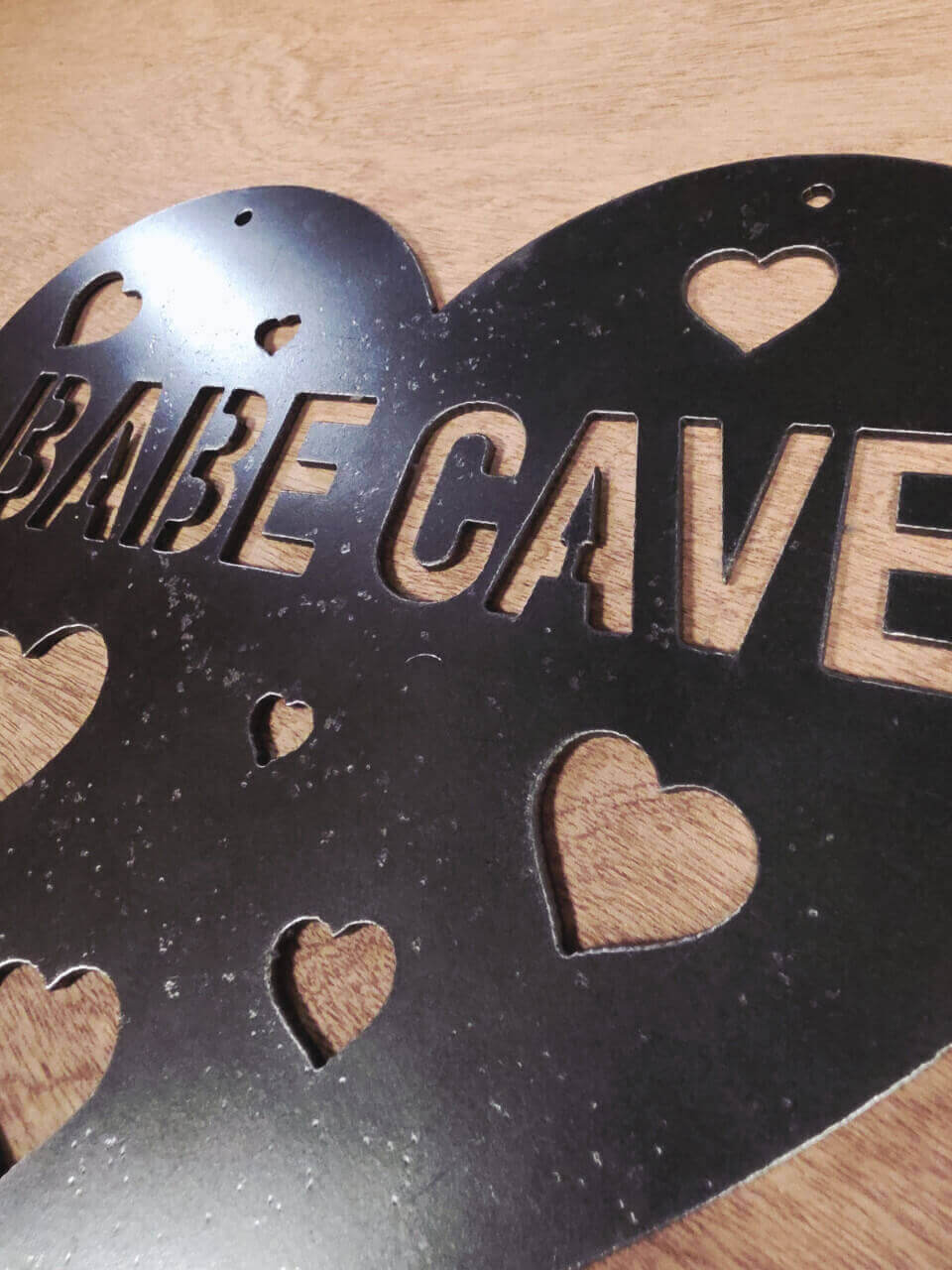Raw steel surface and cut-out hearts on Babe Cave wall sign