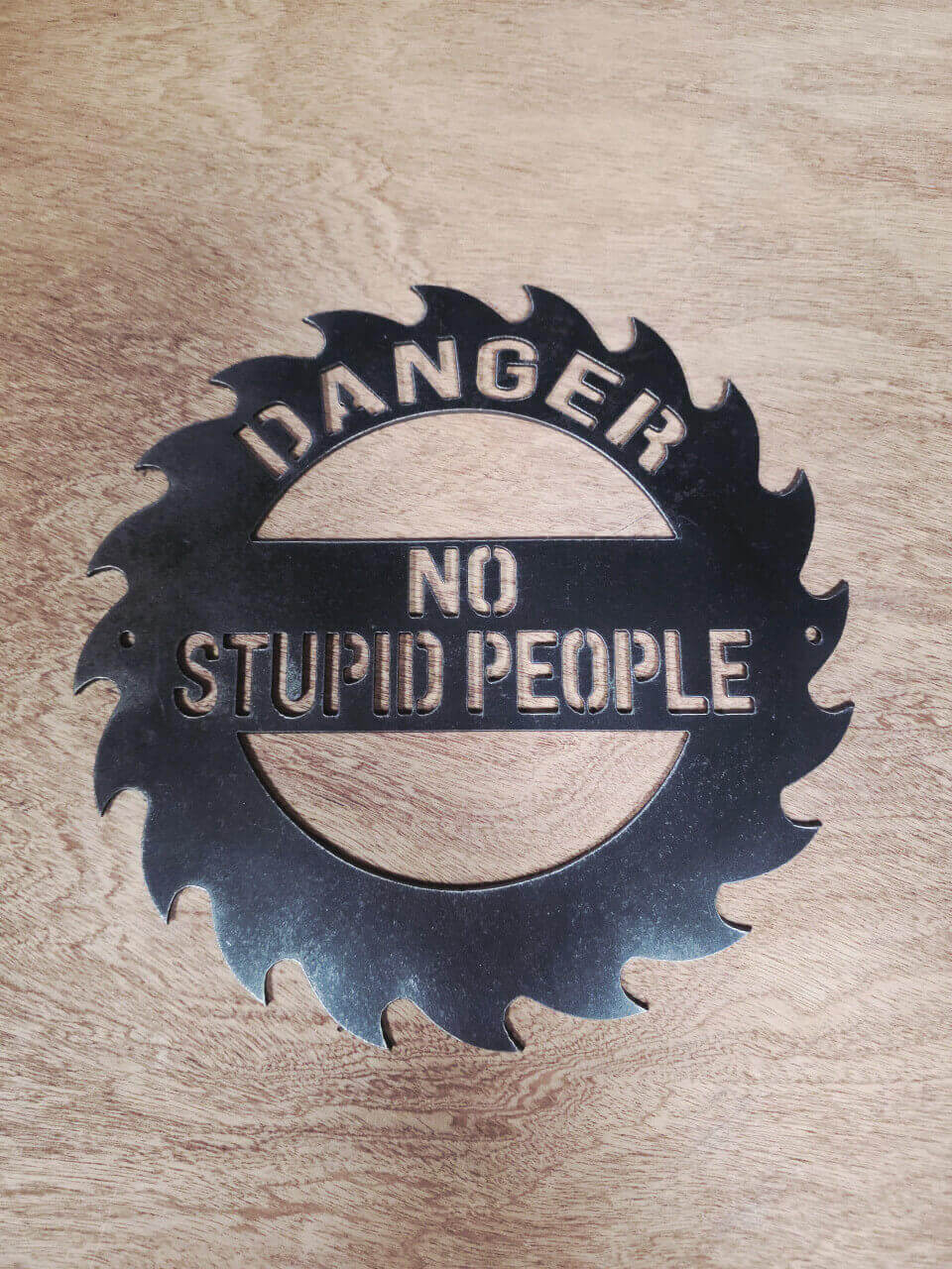 Danger No Stupid People saw-blade shaped raw steel metal sign
