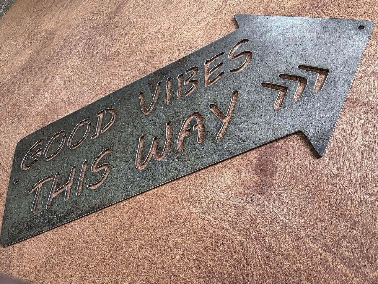 Angled view of Good Vibes This Way arrow metal sign
