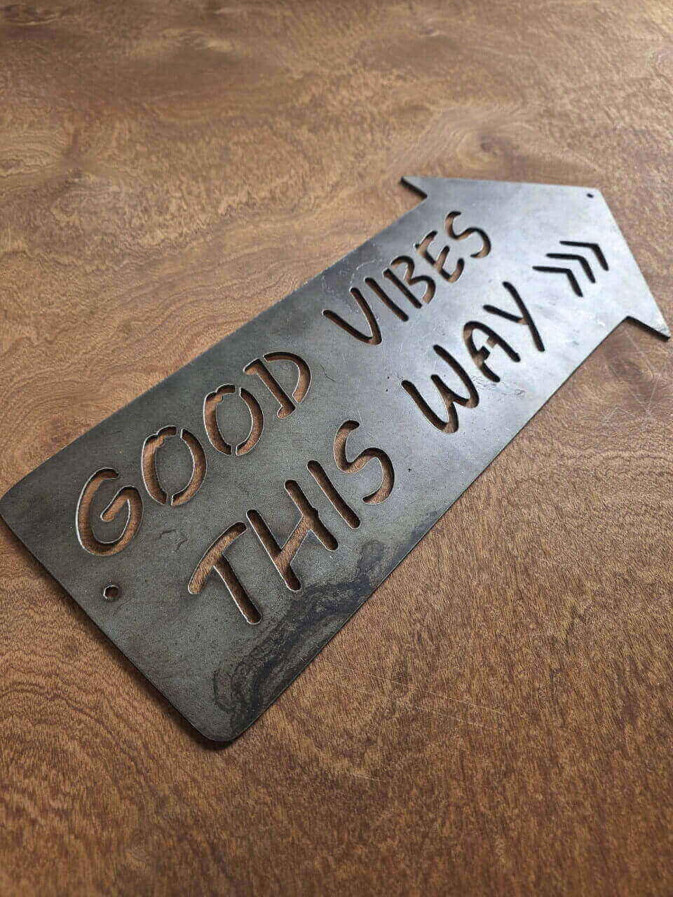 Side-angle view of plasma-cut Good Vibes This Way sign