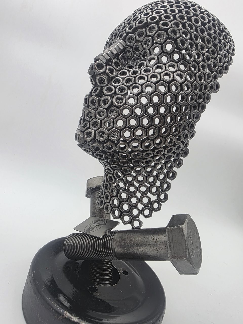 Three-quarter view of Fred the Head metal sculpture with nut-built face and large steel bolts