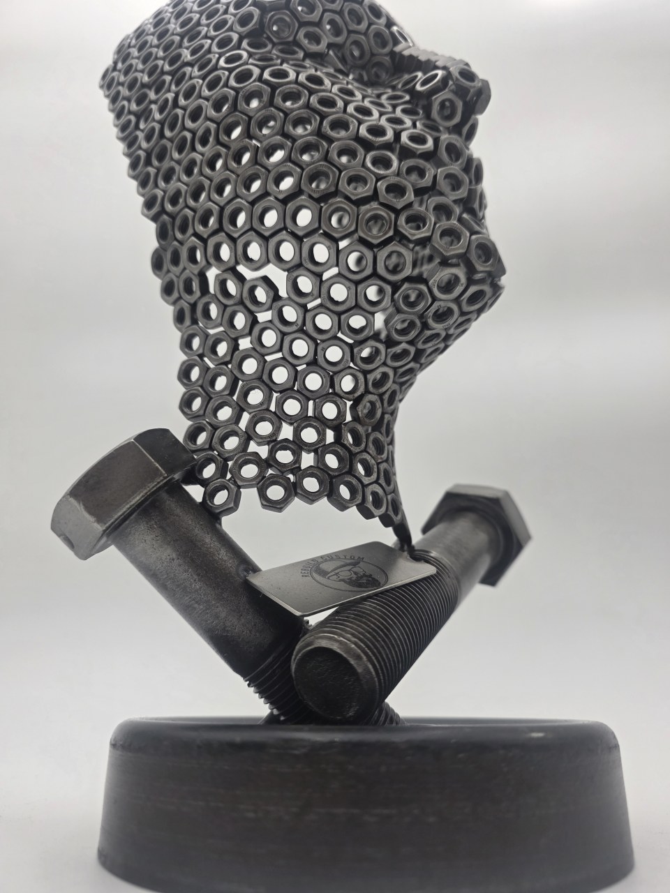 Low side view of Fred the Head sculpture showing the reclaimed circular base and bolt supports