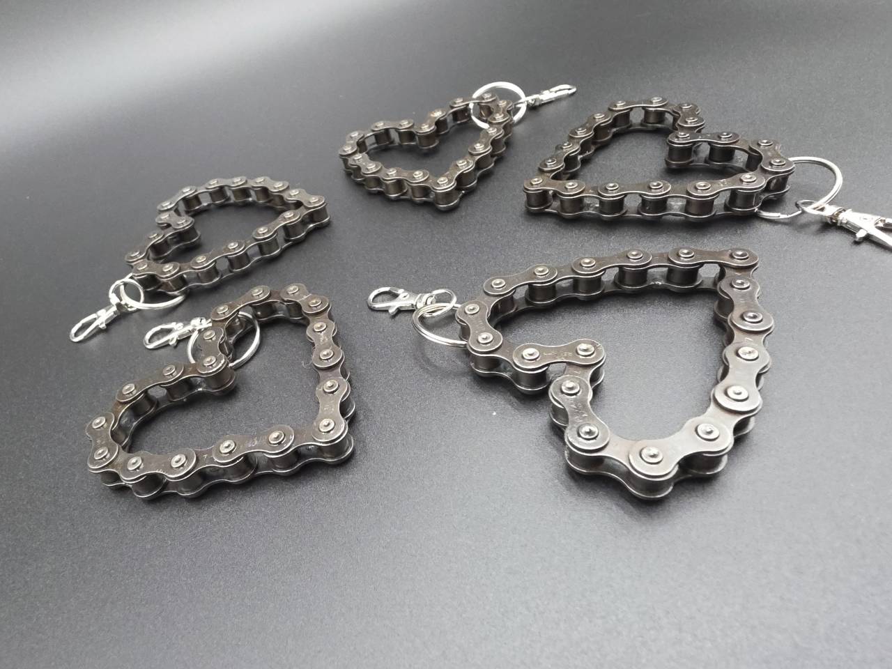 Reclaimed chain heart keyrings with metal attachment clips viewed at an angle
