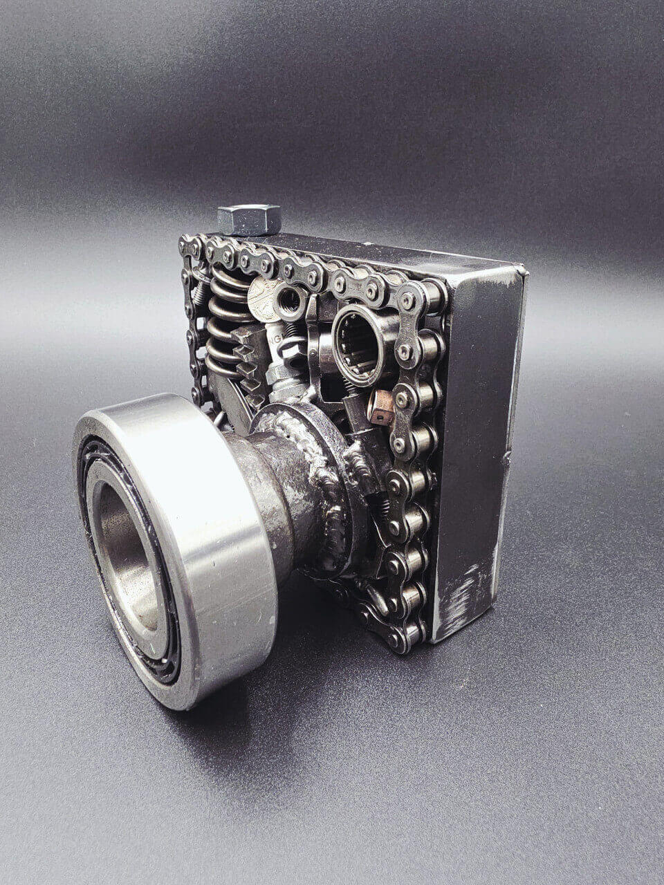 Angled view of reclaimed automotive parts forming a camera sculpture