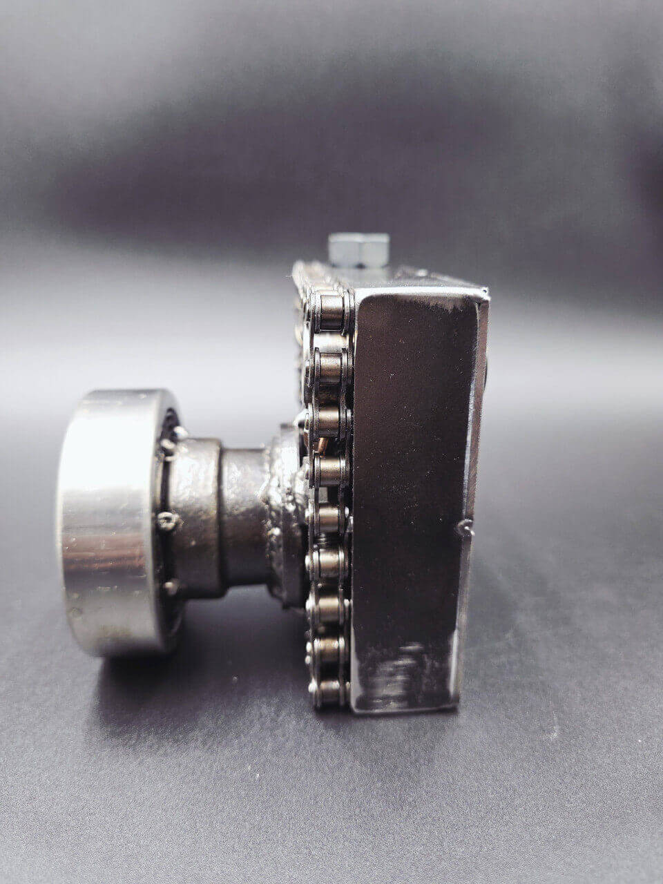 Side view showing the projecting bearing lens on the metal camera sculpture