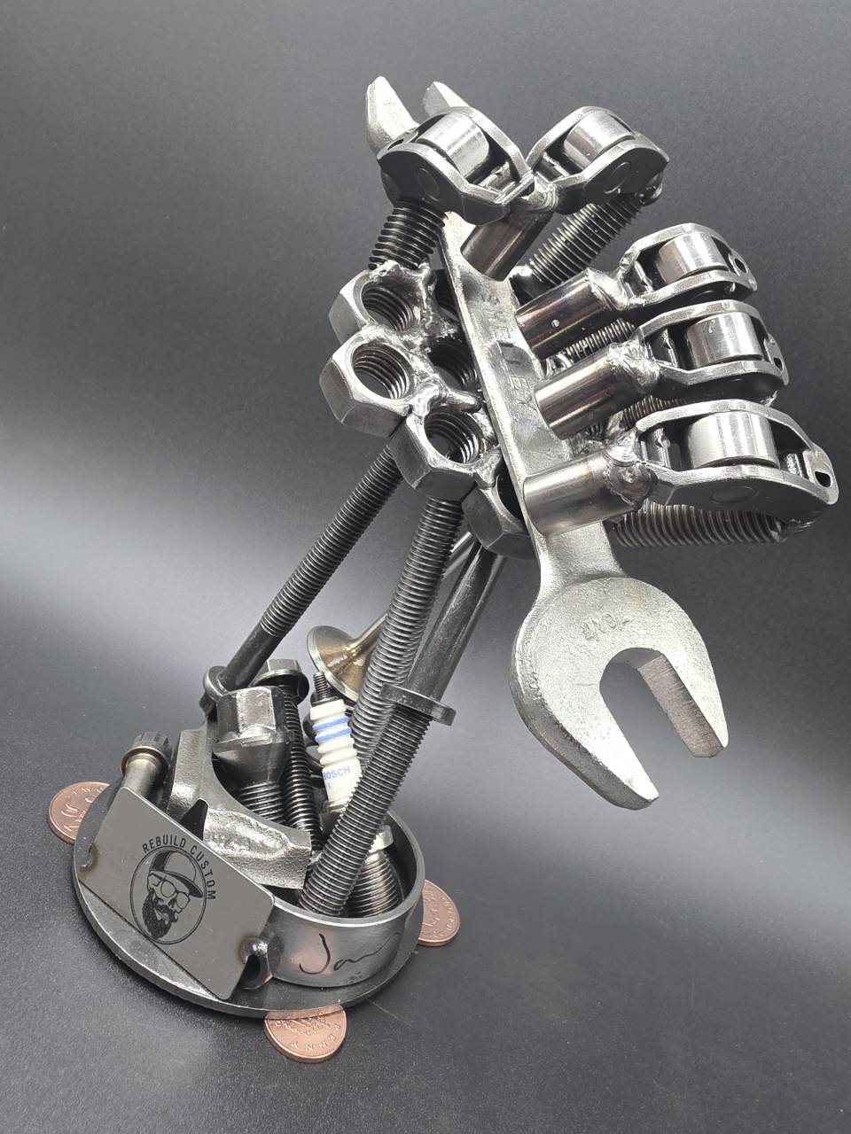 Front three-quarter view of the scrap metal mechanic’s hand holding a spanner