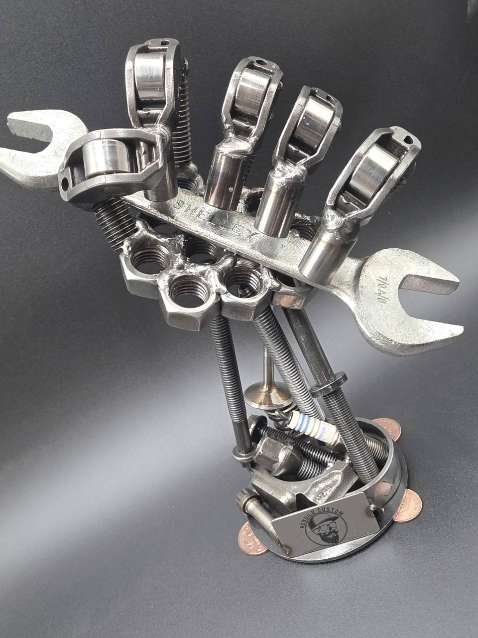 Front view of the mechanic’s hand sculpture with spanner across the steel palm