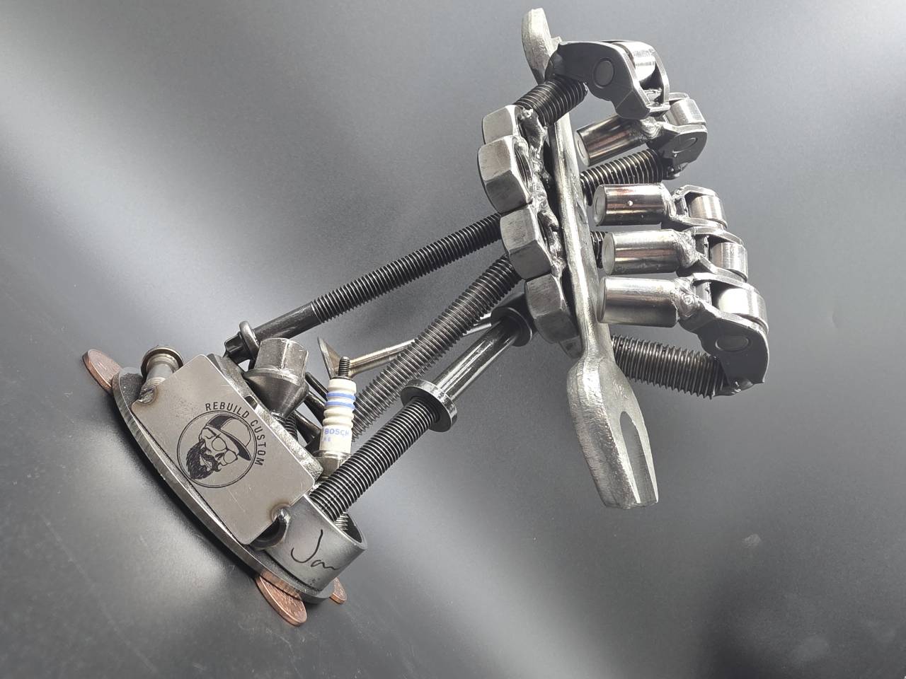 Low side view of the one-off scrap metal hand sculpture and its coin details