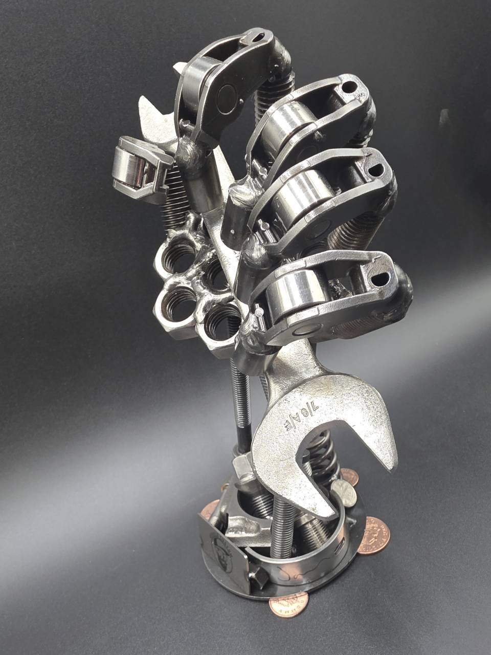 Side profile of the steel hand gripping a spanner above the mechanical base