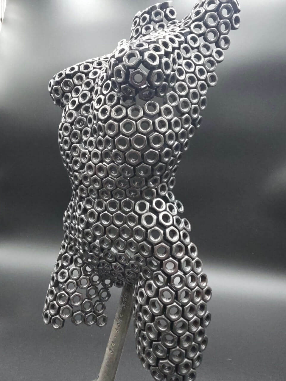 Close-up of the female torso sculpture welded from stacked reclaimed M6 steel nuts Close-up of the female torso sculpture welded from stacked reclaimed M6 steel nuts