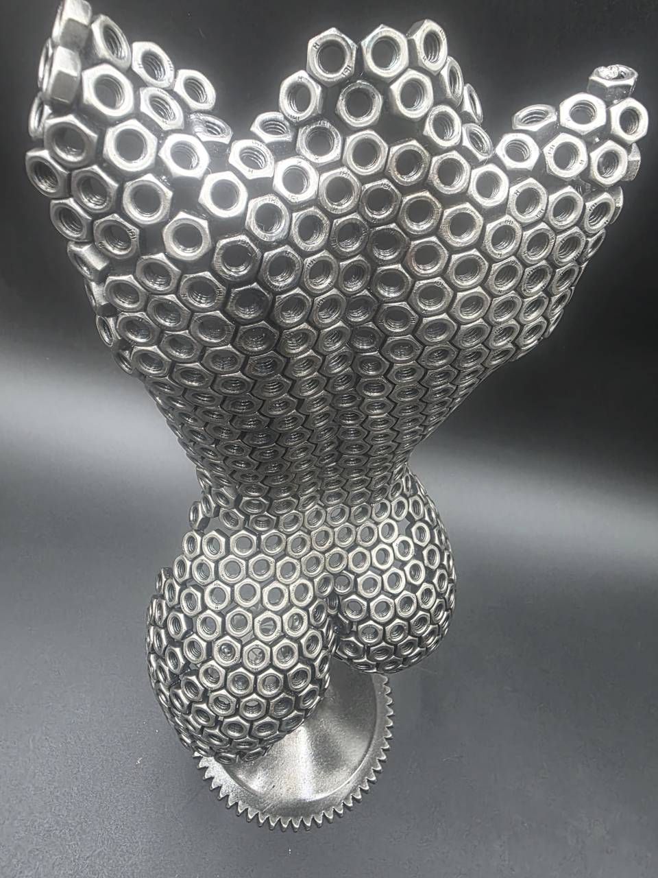 Close high-angle view of the reclaimed steel nut torso sculpture and gear base