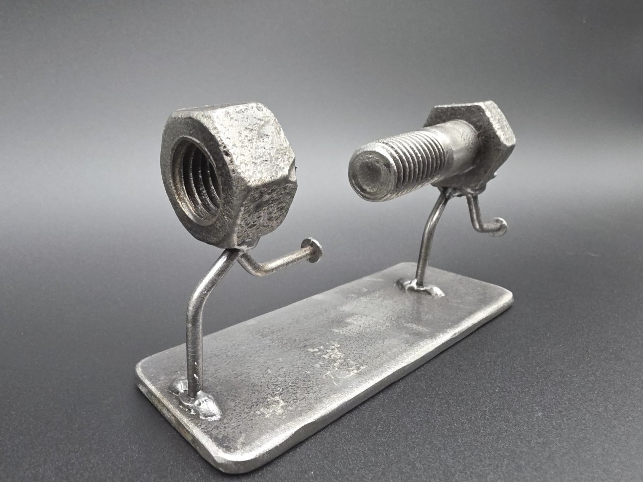 Close angled view of the nut and bolt figures on a steel base