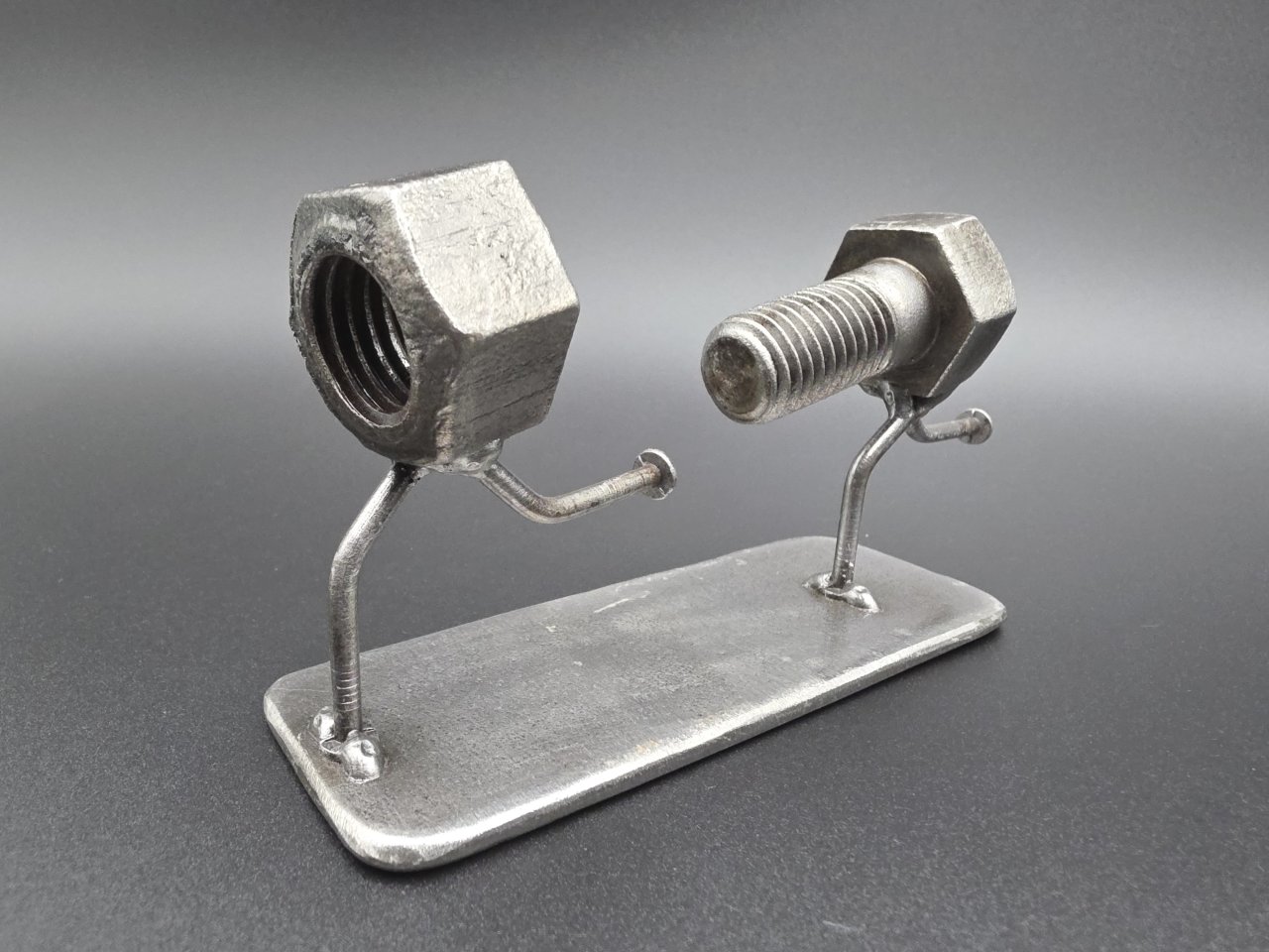 Bolt figure chasing a nut across a reclaimed sheet steel base